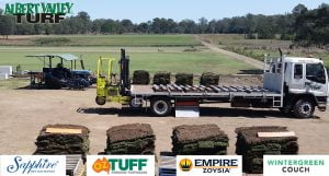 Sapphire, Oz Tuff, Empire Zoysia, and wintergreen couch turfs stacks being loaded onto a truck with grass in the background